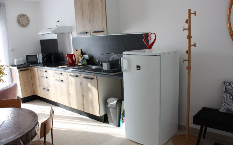 Photo du coin cuisine de l'appartement duo où l'ont voit un réfrigérateur ainsi que la cuisine équipée