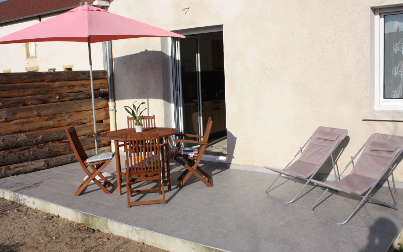 Photo de la terrasse privée de l'appartement duo avec une table d'extérieur et 2 bains de soleil