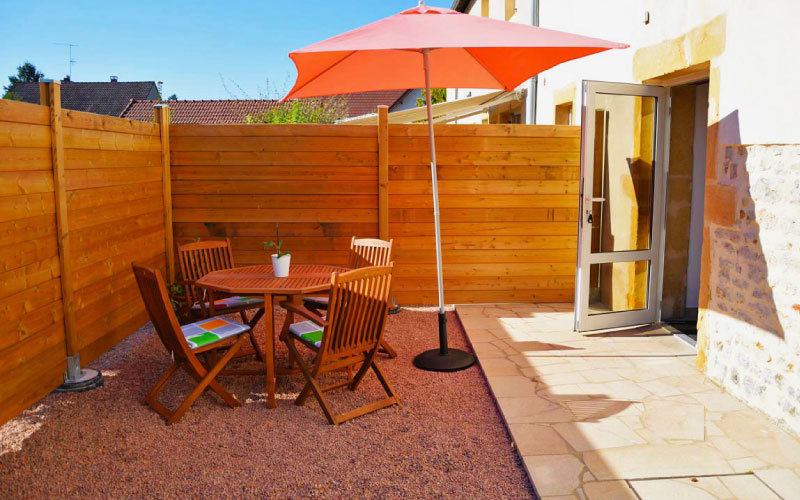 Photo de la terrasse de l'appartement quatuor avec la table d'extérieur, le parasol et l'entrée de l'appartement